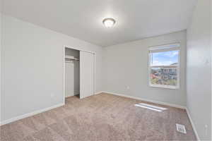 Unfurnished bedroom with carpet floors, baseboards, a closet, and visible vents