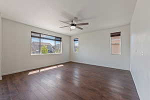 Spare room featuring baseboards, a ceiling fan, and dark wood finished floors