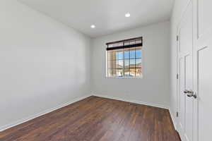 Unfurnished room featuring recessed lighting, baseboards, dark wood finished floors, and visible vents