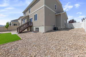 Back of house with central air condition unit, a gate, a fenced backyard, and stucco siding