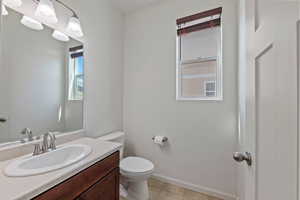 Bathroom featuring baseboards, tile patterned floors, toilet, and vanity