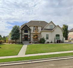 View of front of home with a front yard, stucco siding, and stone siding