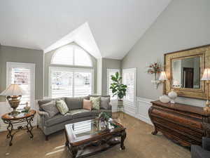 Living room featuring carpet floors, vaulted ceiling, and wainscoting