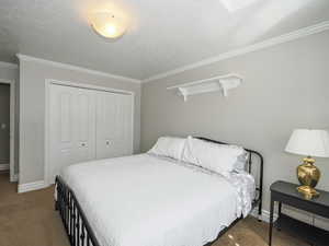 Bedroom featuring a closet, a textured ceiling, baseboards, and carpet