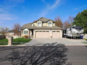Traditional-style house featuring concrete driveway, stucco siding, an attached garage, fence, and a shingled roof