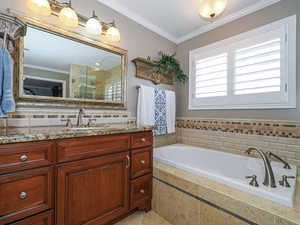 Full bath with a bath, vanity, crown molding, and a shower stall
