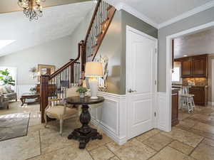Interior space with stairs, ornamental molding, a skylight, stone tile flooring, and wainscoting