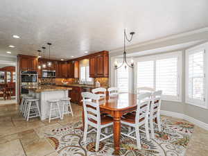 Dining room featuring a textured ceiling, crown molding, baseboards, recessed lighting, and an inviting chandelier