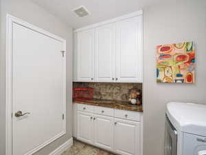 Laundry area with cabinet space, visible vents, and separate washer and dryer
