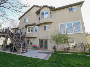 Back of house with a patio, stairway, stucco siding, and a yard