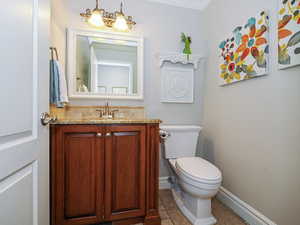 Half bath featuring toilet, vanity, and baseboards