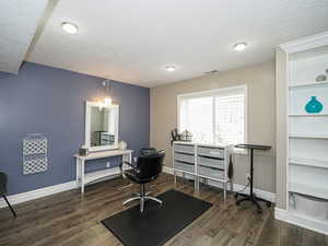 Office space with visible vents, a textured ceiling, baseboards, and wood finished floors