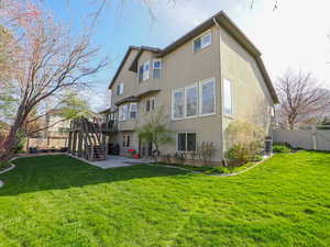 Rear view of property with a lawn, a patio area, stucco siding, and a fenced backyard