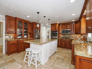 Kitchen featuring a sink, recessed lighting, stone tile floors, and appliances with stainless steel finishes