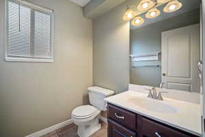 Bathroom with baseboards, toilet, tile patterned flooring, and vanity