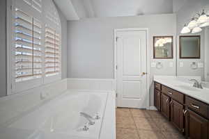 Bathroom featuring tile patterned floors, vanity, and a bath