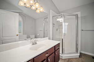 Full bath with a stall shower, tile patterned floors, toilet, vanity, and lofted ceiling