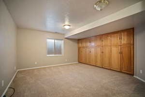 Unfurnished bedroom with baseboards, a textured ceiling, and light carpet