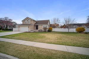 View of front facade featuring fence, an attached garage, concrete driveway, a front lawn, and stucco siding