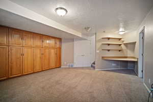 Finished basement featuring light colored carpet, visible vents, stairs, and baseboards