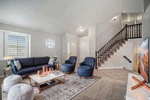 Living room featuring baseboards, stairway, vaulted ceiling, and tile patterned flooring