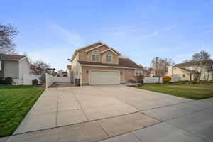 View of front of property featuring driveway, a front yard, stucco siding, fence, and a garage