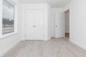 Unfurnished bedroom featuring a closet, baseboards, and carpet