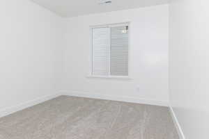 Carpeted spare room featuring baseboards and visible vents