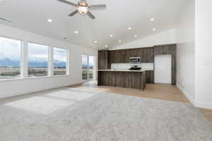 Kitchen with open floor plan, ceiling fan, visible vents, dark brown cabinets, and appliances with stainless steel finishes