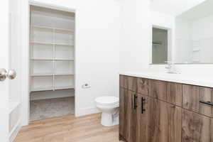 Bathroom featuring toilet, vanity, and wood finished floors