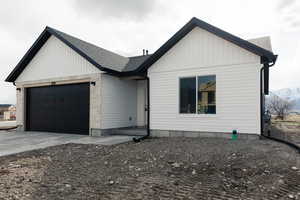 Modern farmhouse style home featuring board and batten siding, driveway, a garage, and roof with shingles
