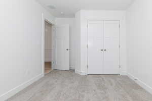 Unfurnished bedroom featuring baseboards, visible vents, a closet, and carpet floors