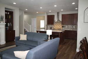 Living area featuring a textured ceiling, dark wood-type flooring, stairs, and recessed lighting
