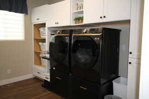 Clothes washing area featuring washing machine and clothes dryer, cabinet space, and dark wood-type flooring