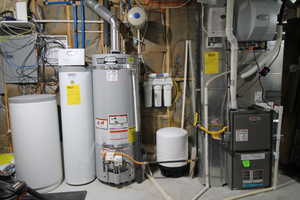 Utility room featuring heating unit and gas water heater