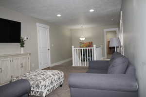 Living room with carpet flooring, a textured ceiling, baseboards, and recessed lighting