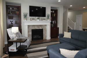 Living area featuring stairs, a fireplace, wood finished floors, and recessed lighting