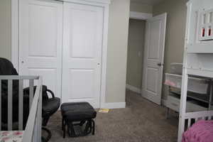 Bedroom featuring baseboards, carpet floors, and a closet