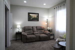 Carpeted living area with recessed lighting just off the front door