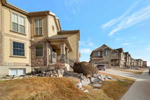 View of home's exterior with stone siding, a residential view, concrete driveway, and a garage
