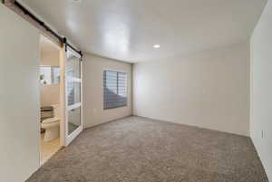 Unfurnished bedroom with carpet, a barn door, and recessed lighting