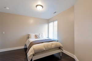Bedroom with baseboards, visible vents, and dark wood finished floors