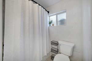 Bathroom featuring toilet and tile walls