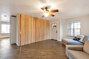 Living room with baseboards, a ceiling fan, and dark wood-style floors