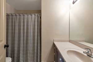Bathroom with toilet, vanity, and a shower with curtain