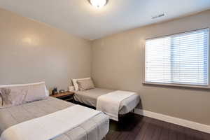 Bedroom with baseboards, visible vents, and wood finished floors