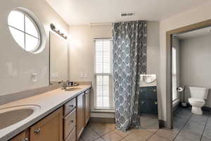 Bathroom featuring tile patterned floors, visible vents, toilet, and a sink