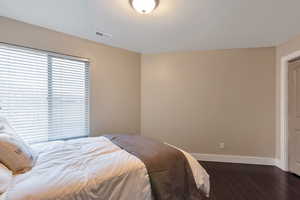 Bedroom with baseboards, visible vents, and dark wood-style flooring
