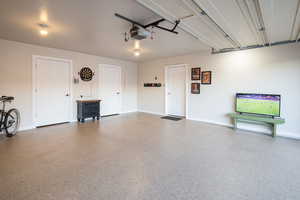 Garage featuring baseboards and a garage door opener