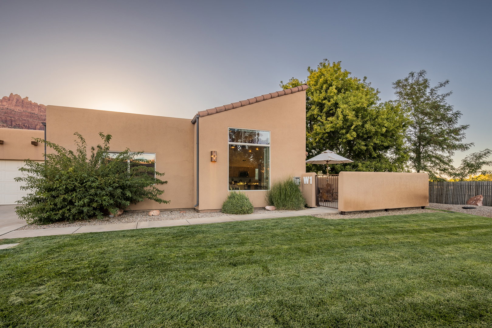Back of house with a lawn, a gate, fence, and stucco siding